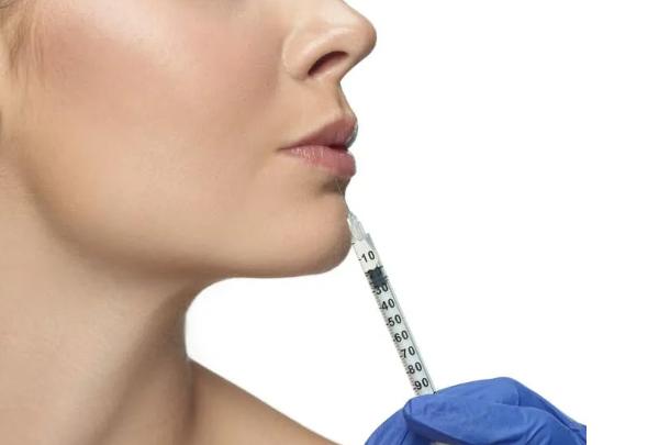 A professional applying facial fillers to a client’s cheek for skin rejuvenation.